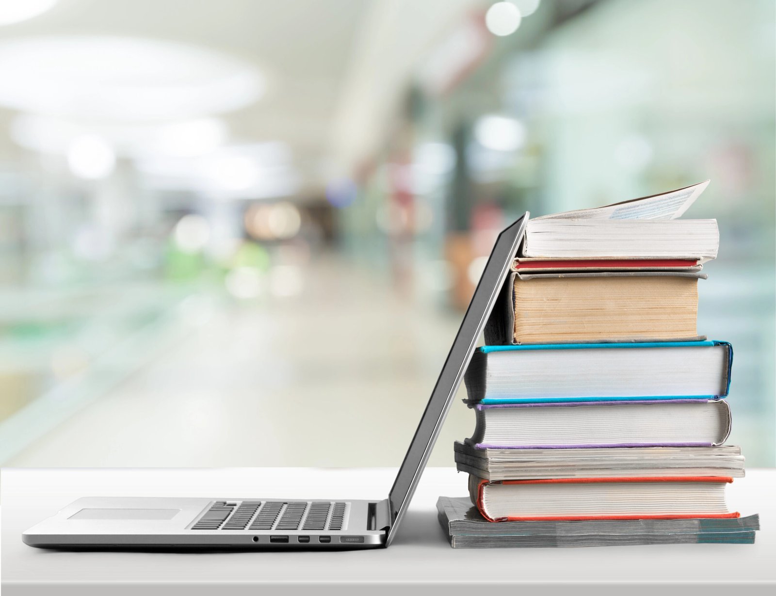 A laptop leaning against a stack of books